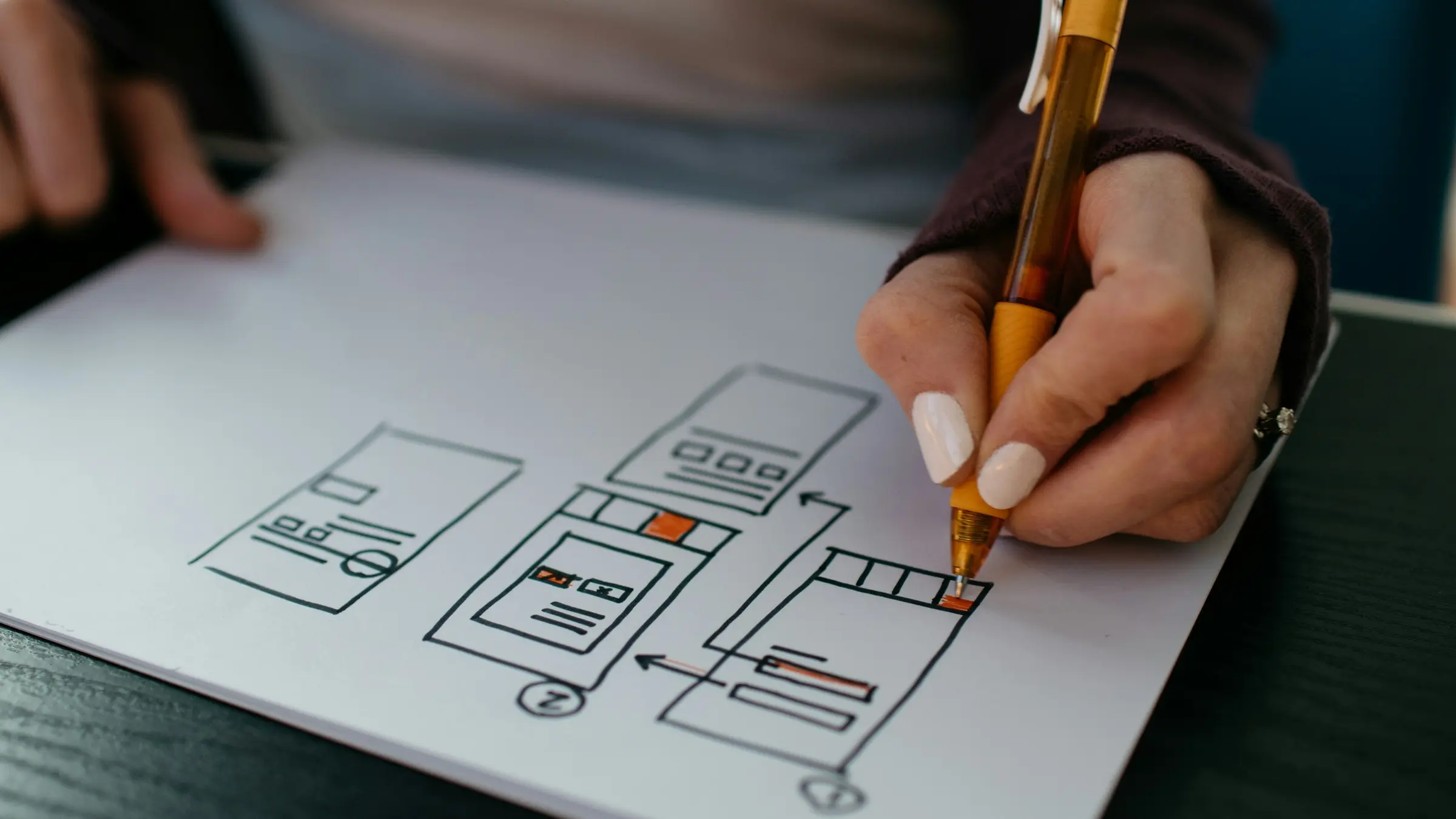 Hand sketching mobile app wireframes on paper