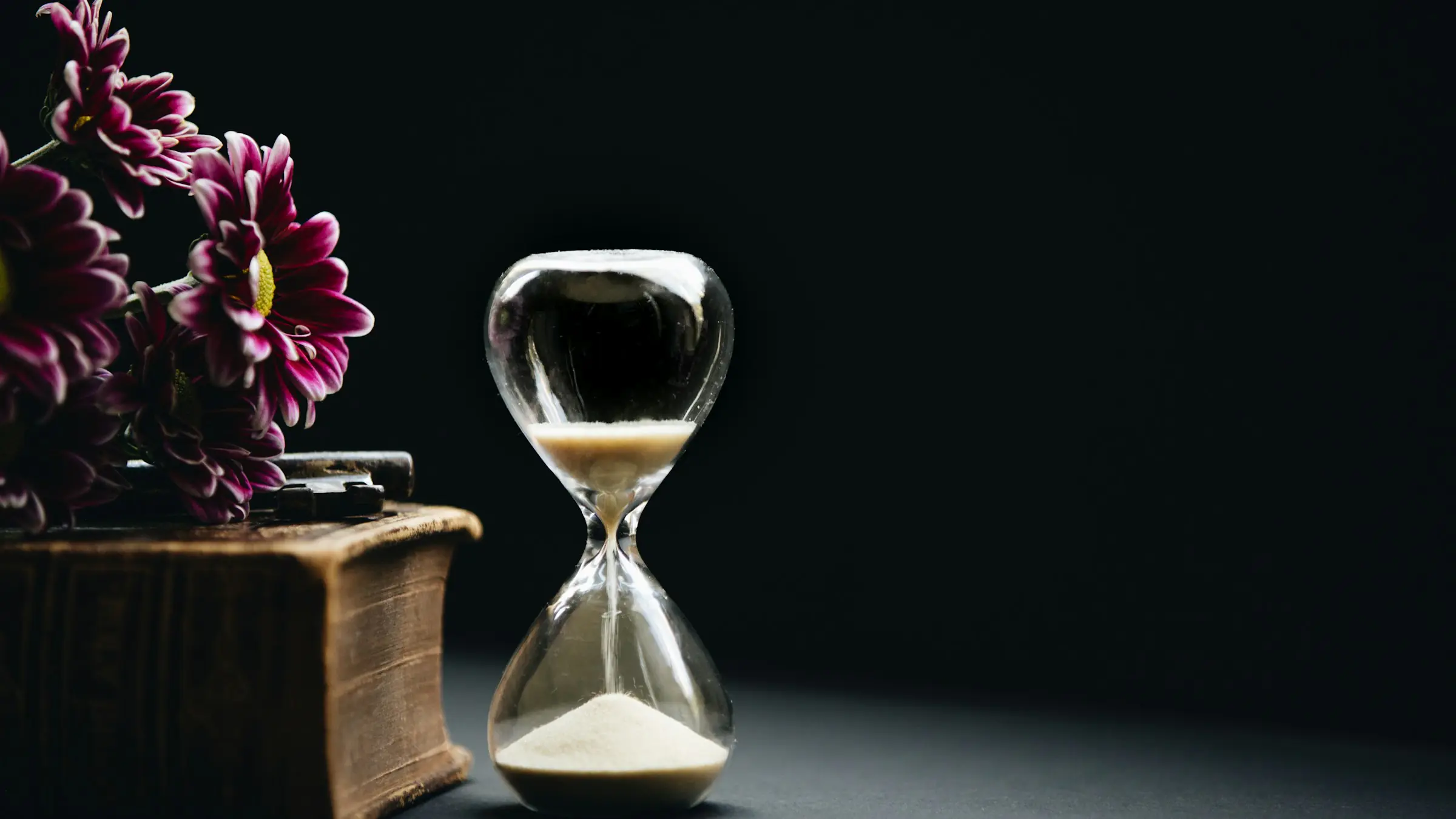 Hourglass with sand running on a dark background