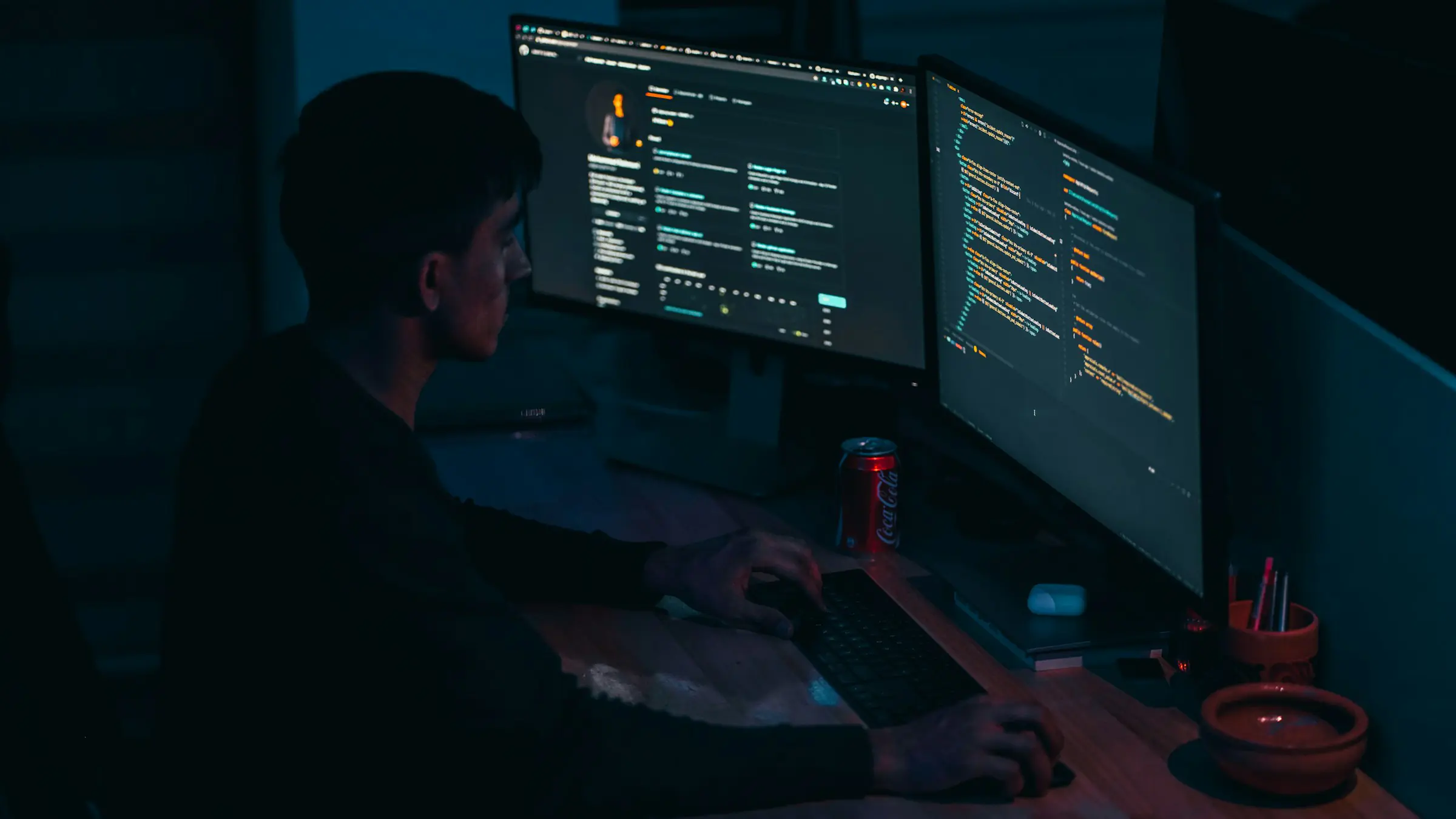 Developer working at multiple monitors in a dark room