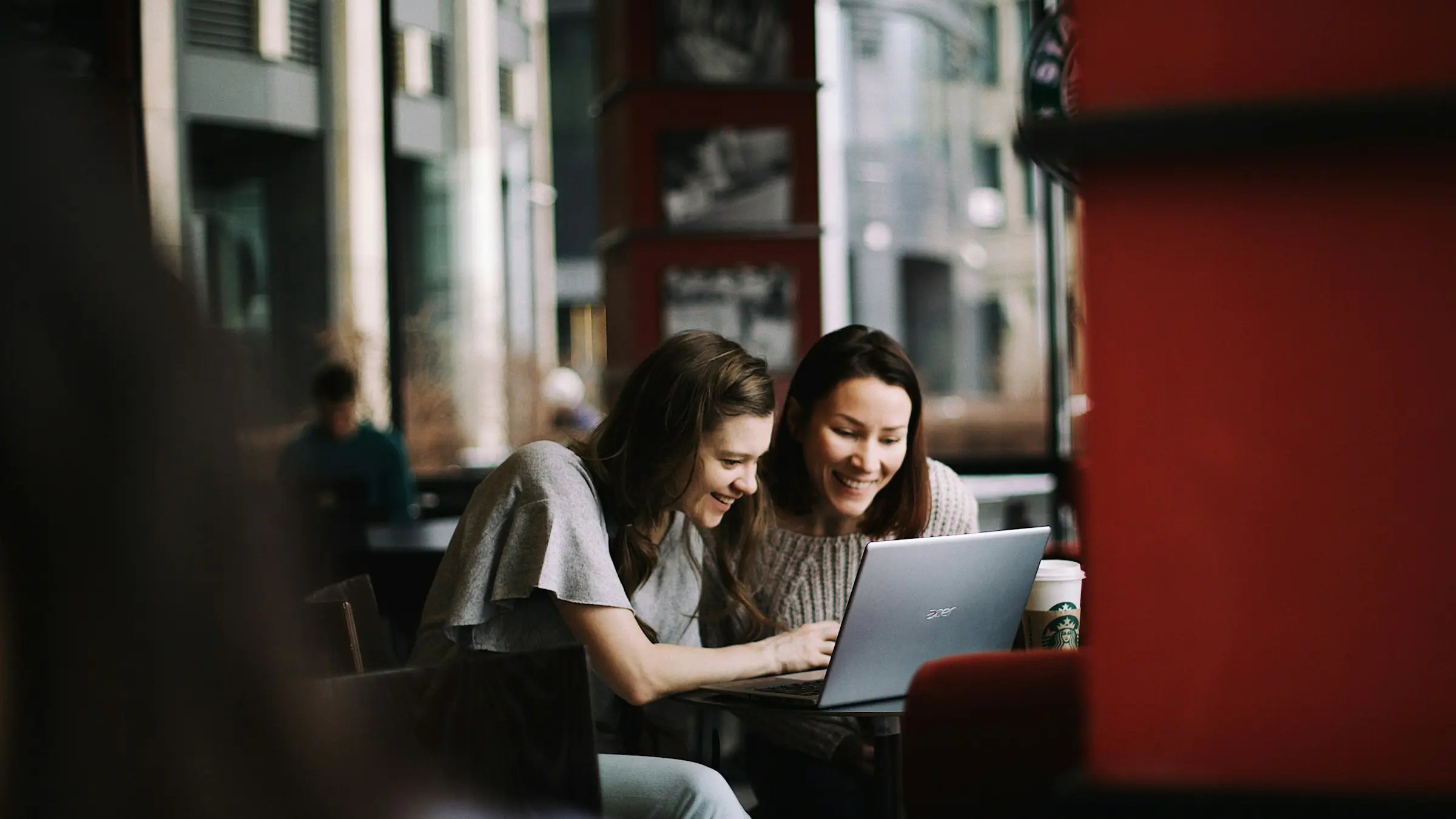 Two people working together on a laptop in a cafe