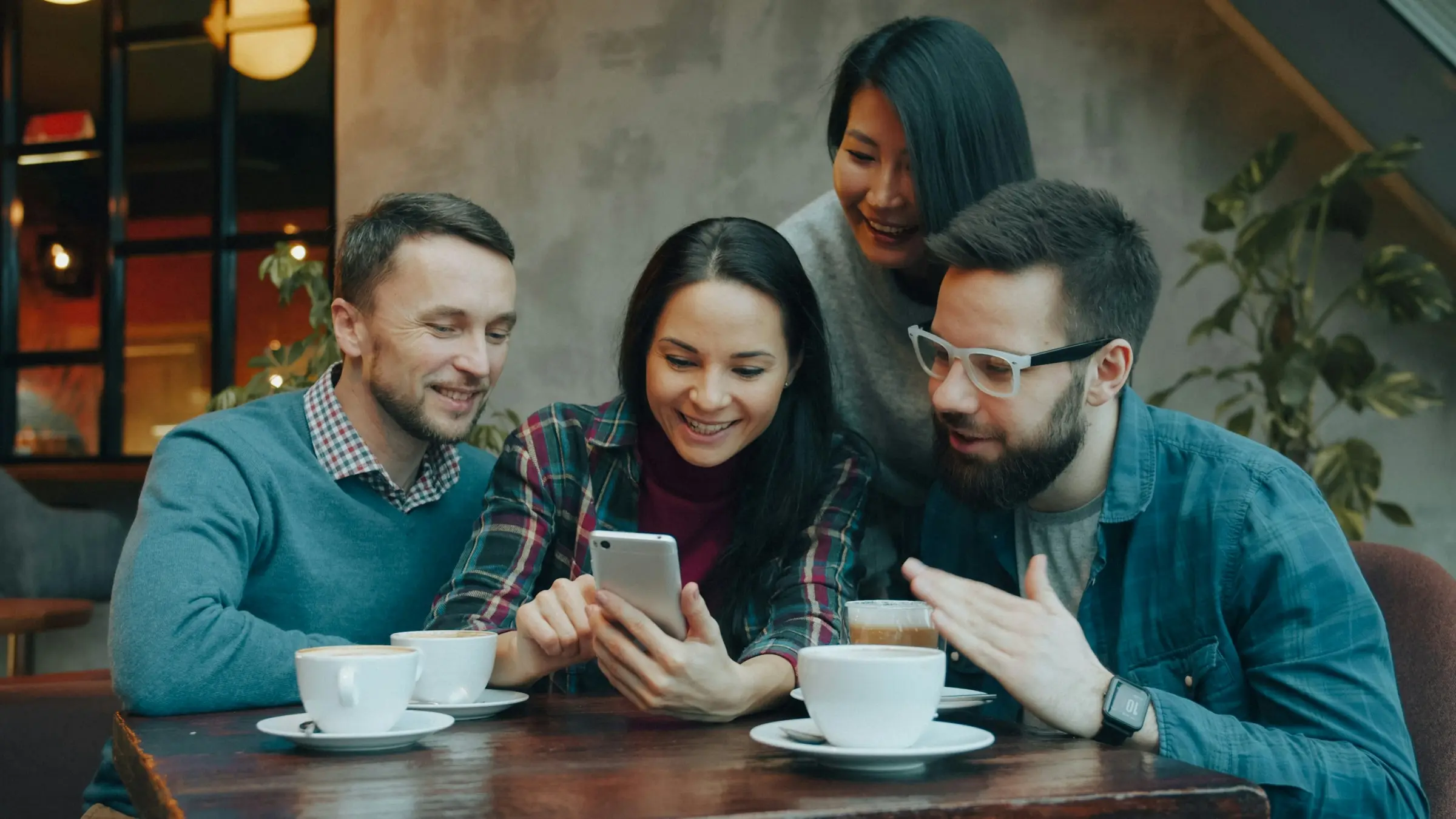 Friends at a cafe looking at a phone together