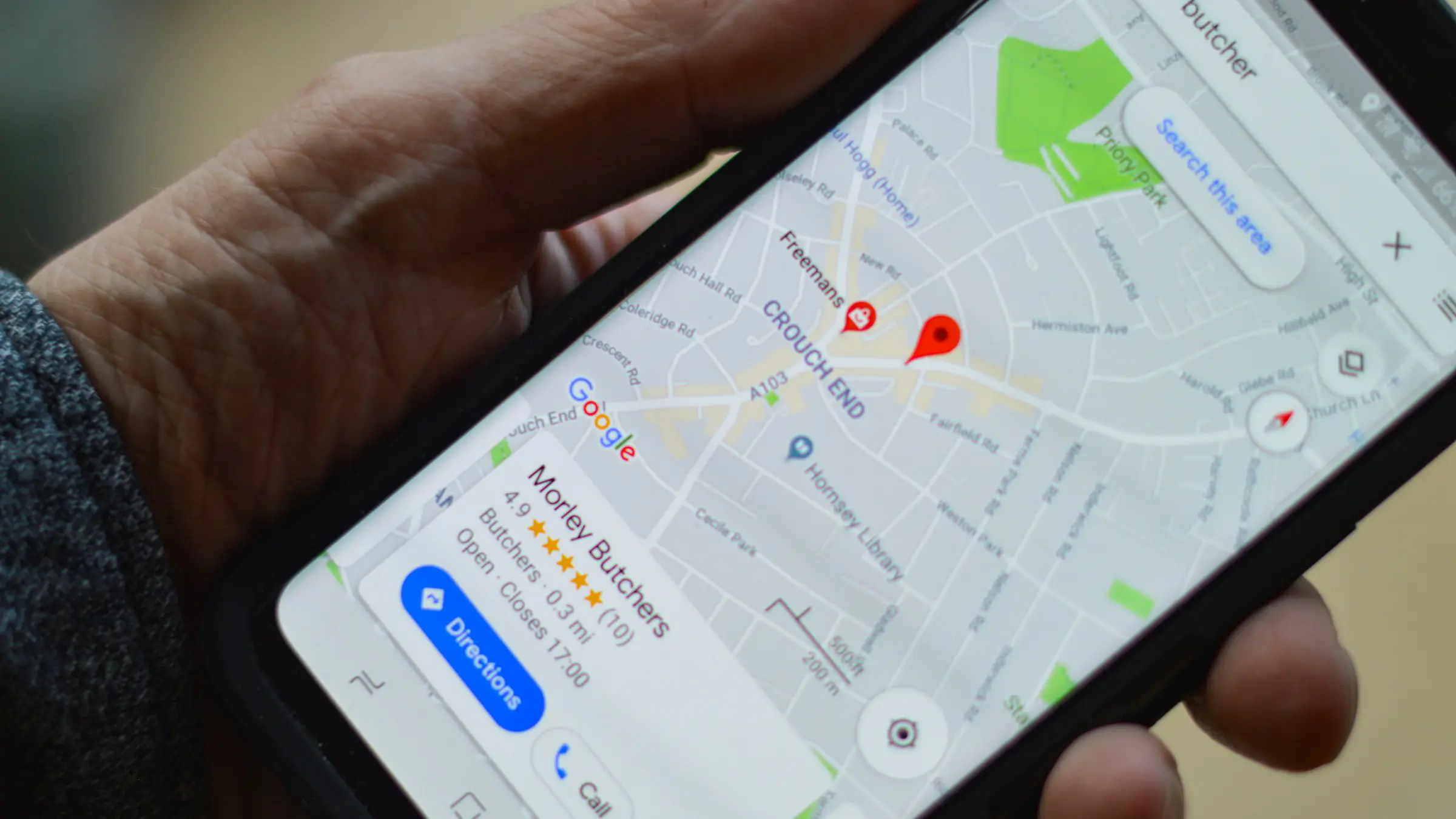 Hand holding a phone showing a Google Maps search for nearby businesses
