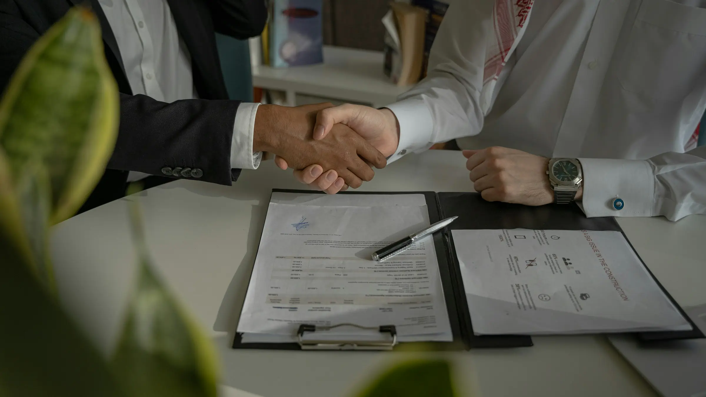 Handshake over a signed contract on a desk